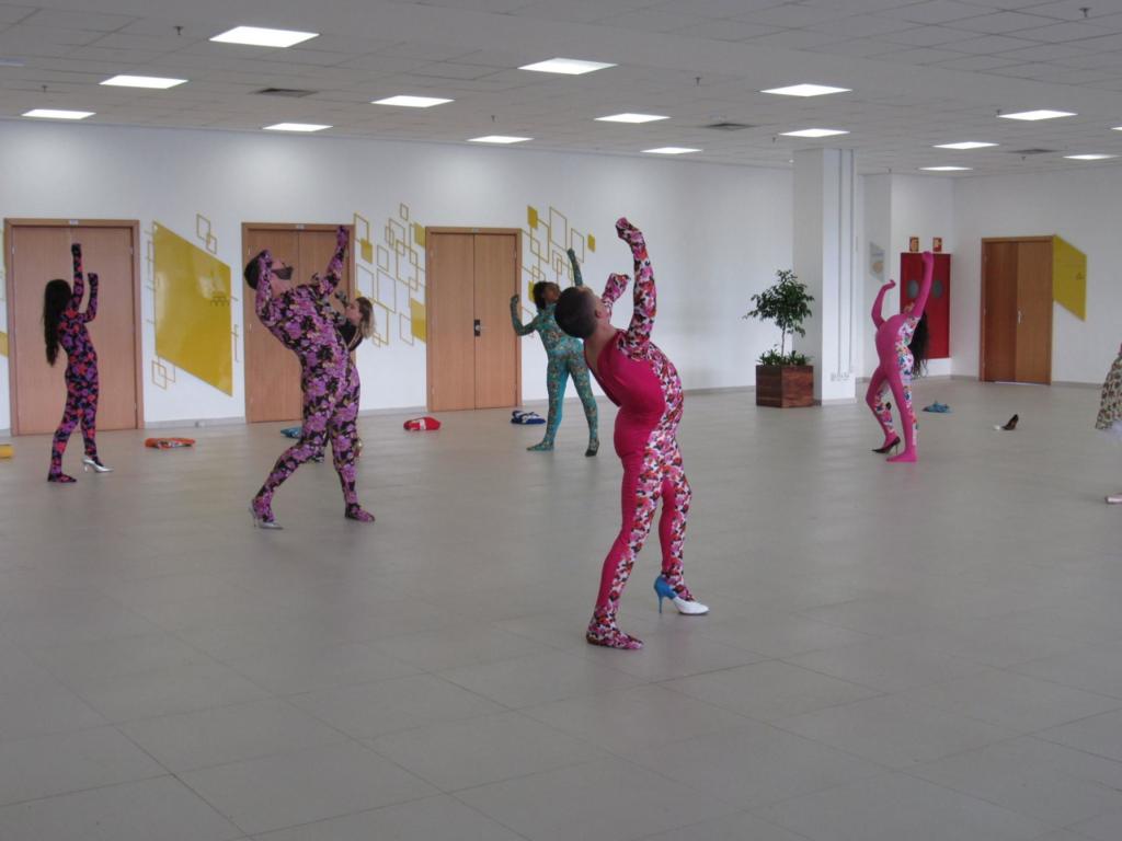Dançarinos vestidos com macacões coloridos dançando no hall do Centro de Convenções