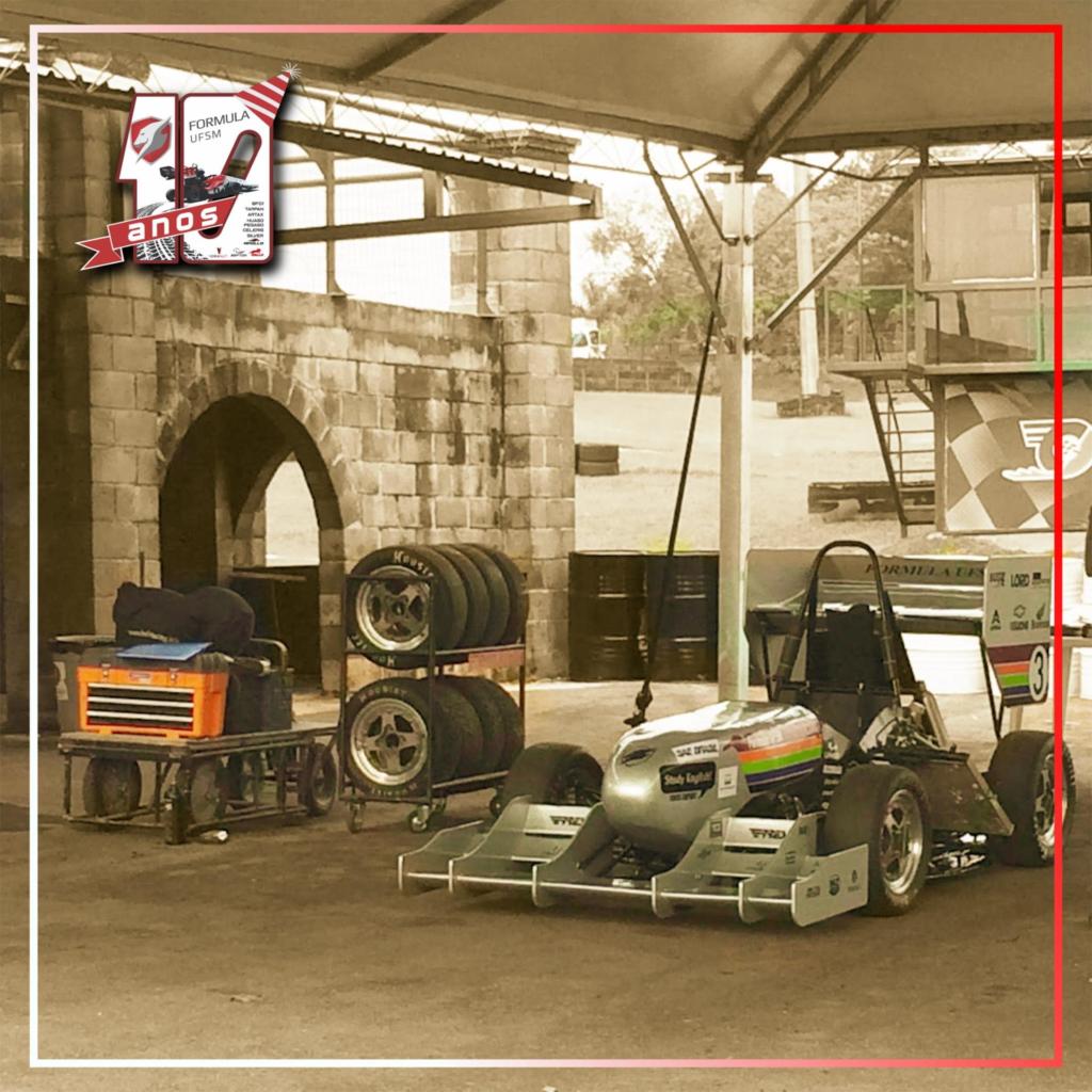 Na foto consta um carro. Este carro possui as mesmas estruturas que um de fórmula 1. Na foto aparece também pneus enfileirados prontos para serem usados