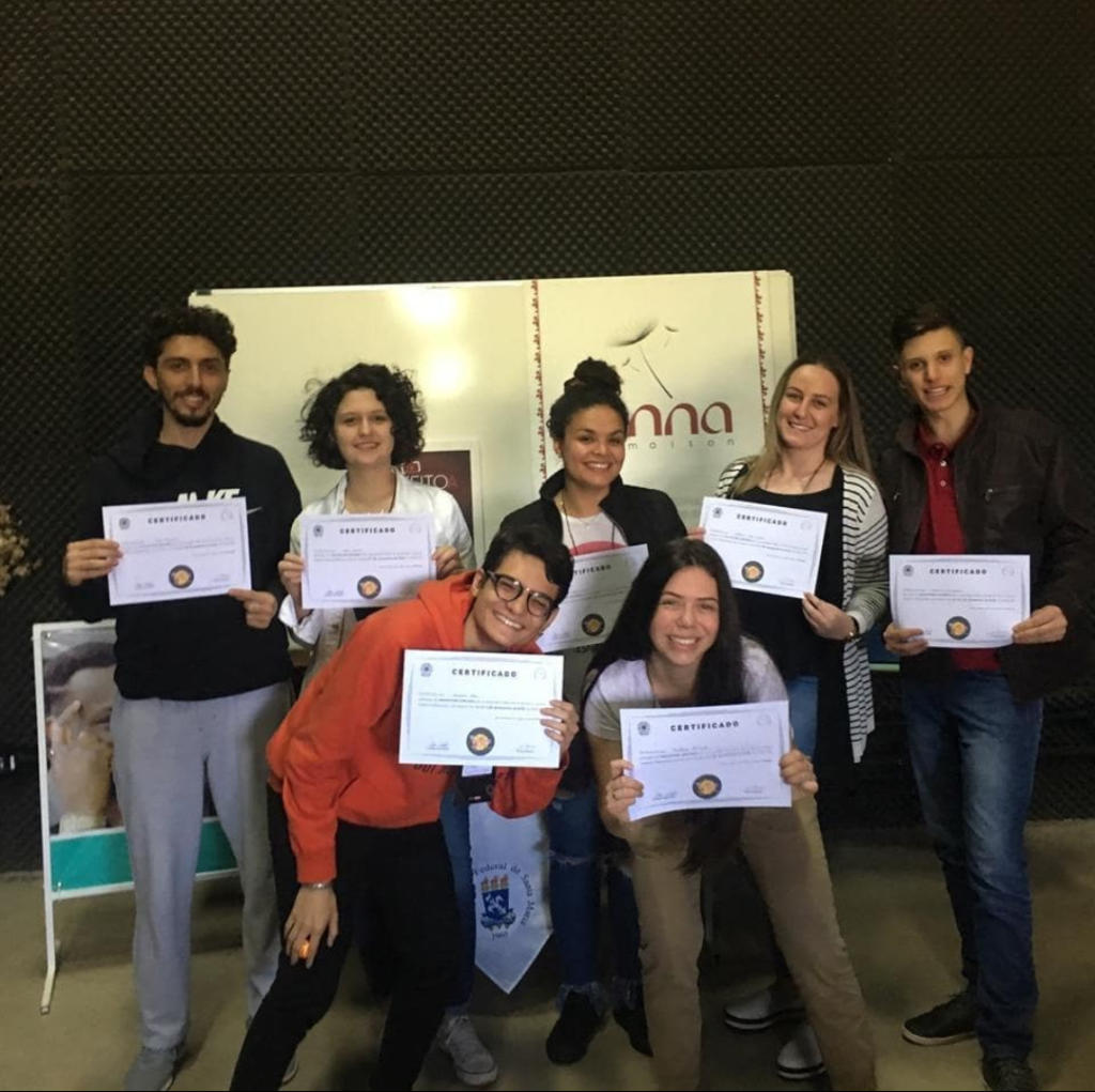 Sete estudantes em pé segurando certificado