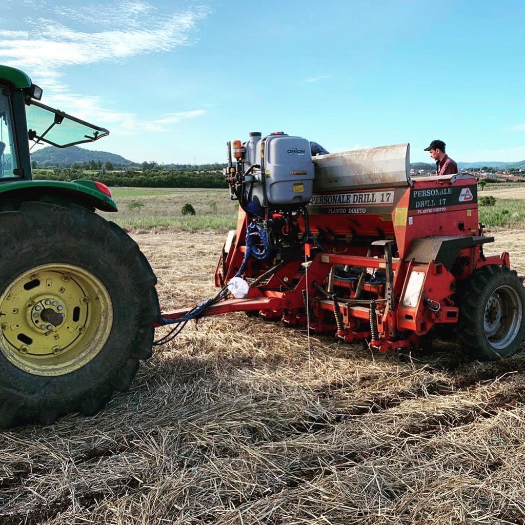 Foto de um trator puxando uma máquina agrícola em um campo.