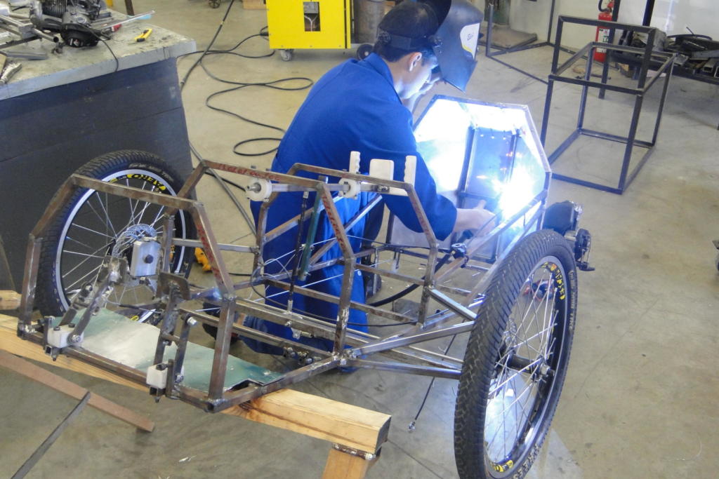 Menino paramentado soldando carro