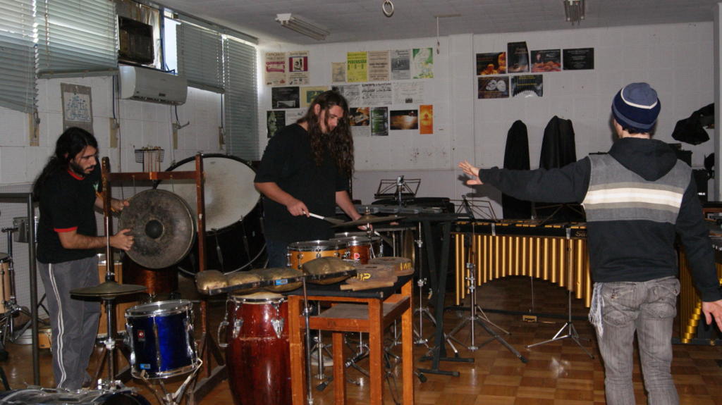 3 homens tocando instrumentos em um estúdio de música
