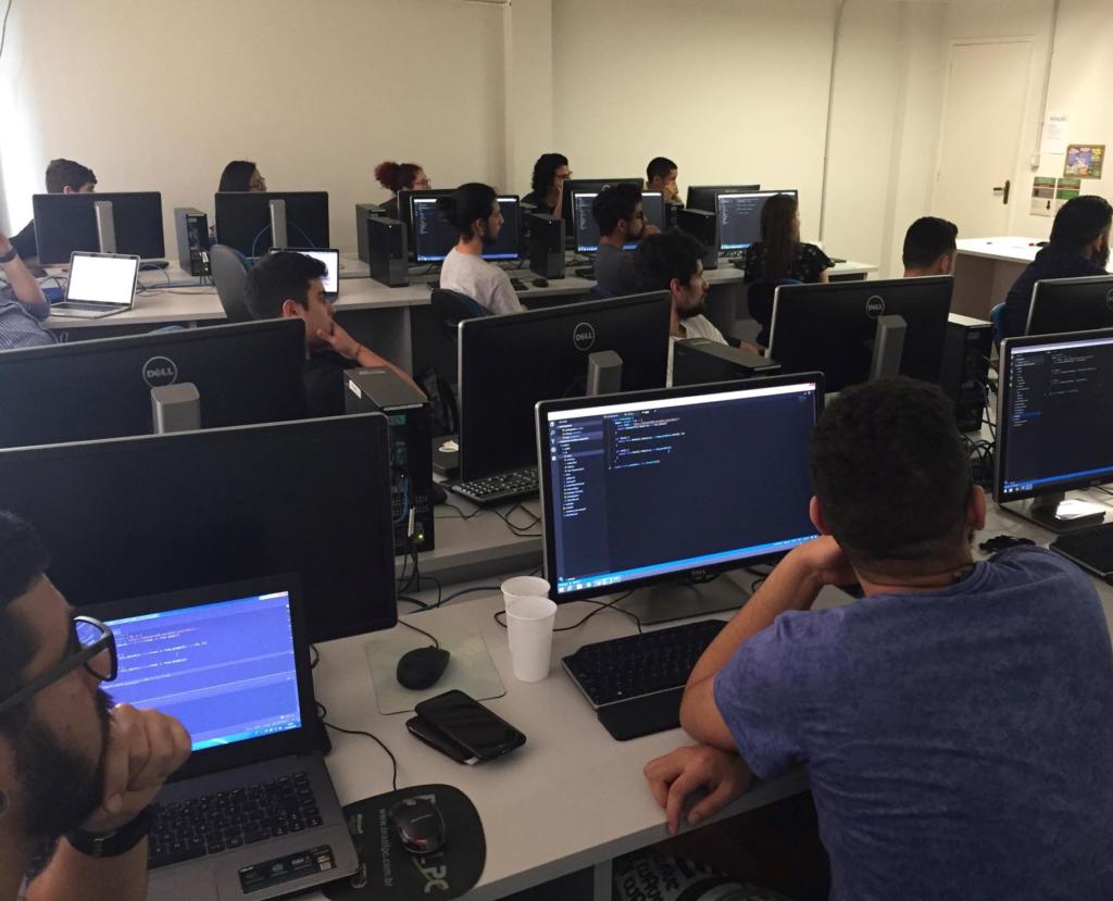 Um laboratório de informática cheio de computador e alunos durante uma aula