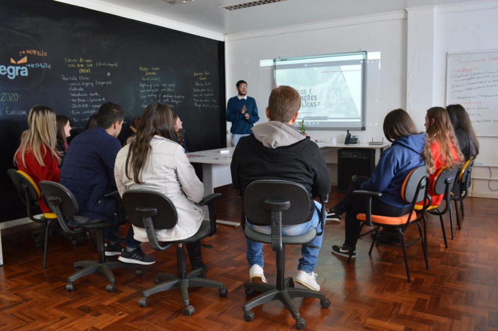 Laboratório com diversos estudantes sentados em torno de uma mesa de reuniões