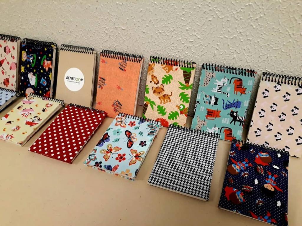 Foto de cadernetas com capas forradas de tecido dispostas em uma bancada