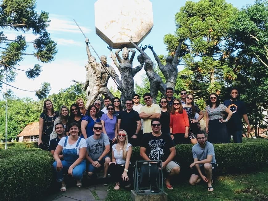 Foto de diversas pessoas em pé em uma praça em frente a um monumento