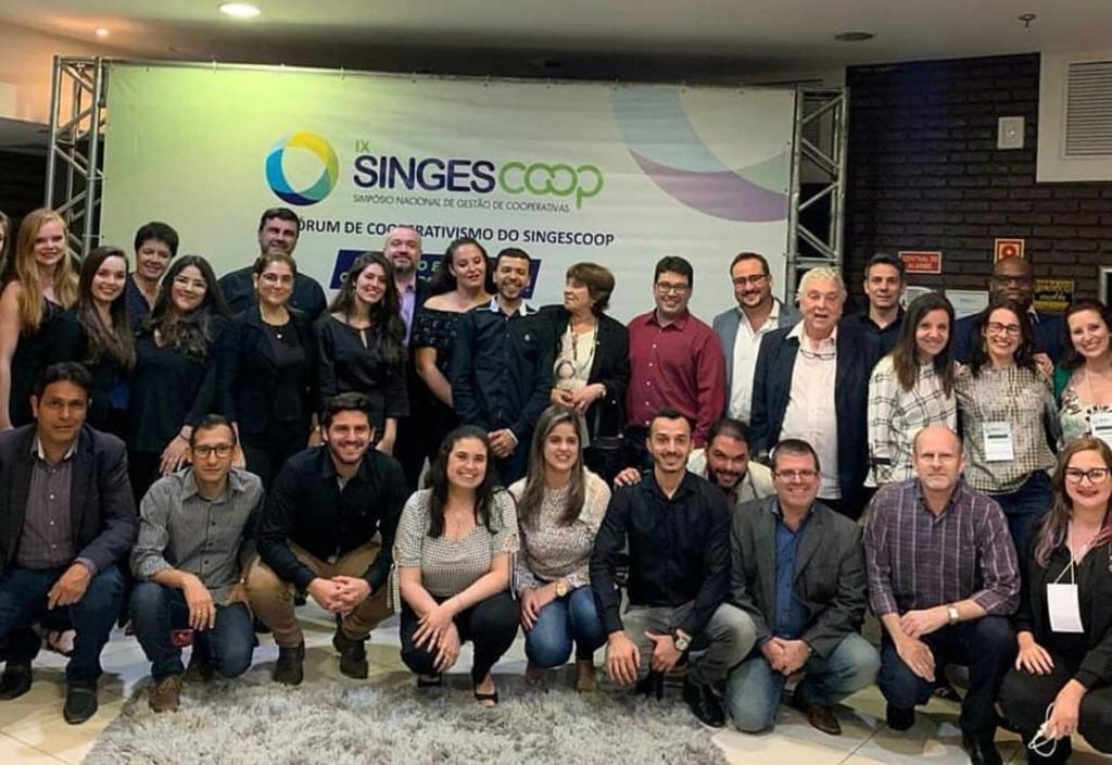 Foto de diversas pessoas em frente a um banner de evento