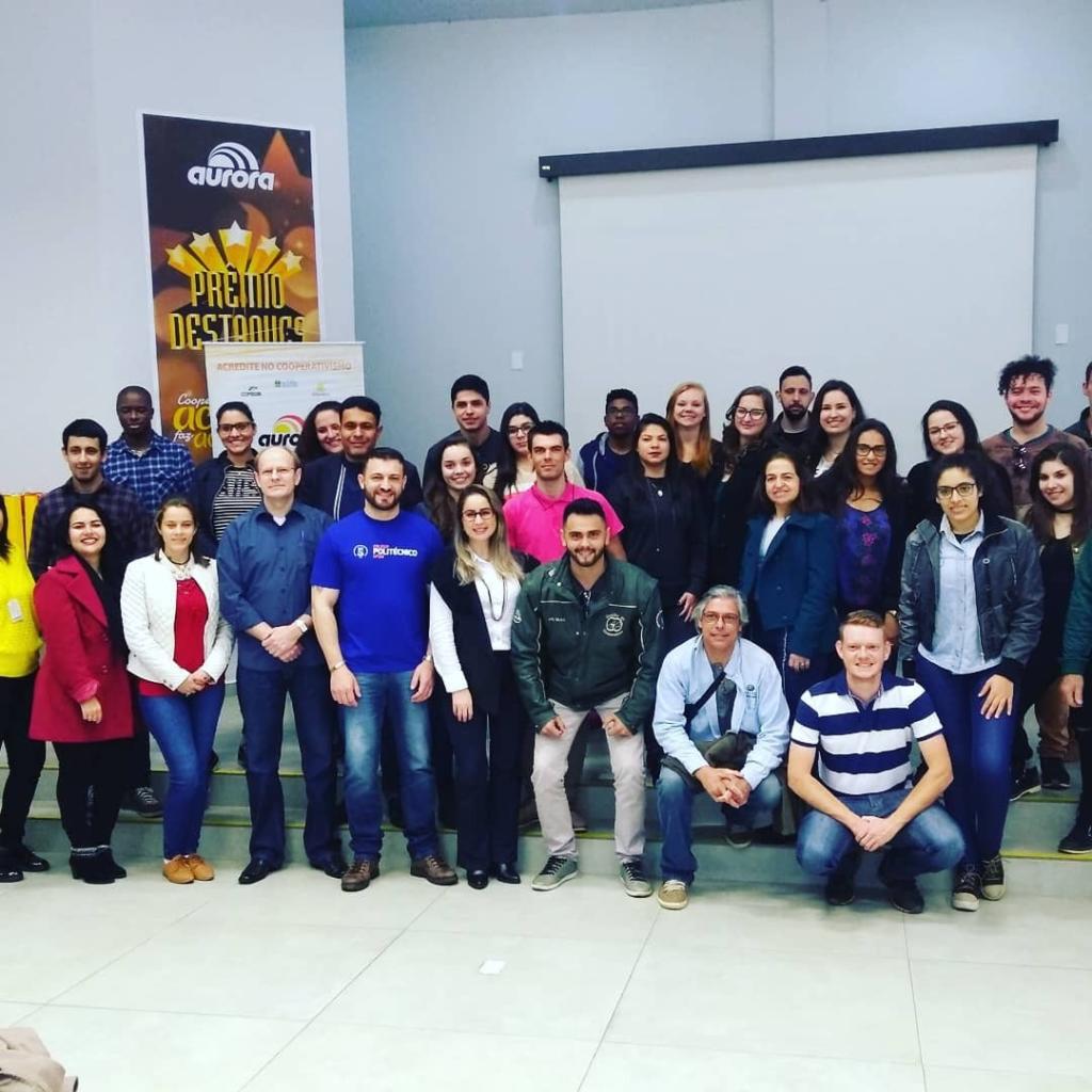 Foto de diversas pessoas em frente a banner de evento