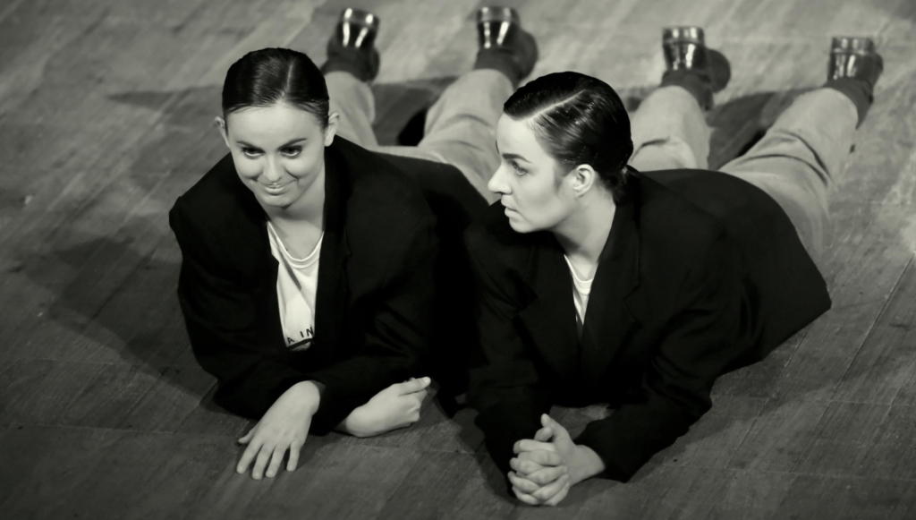Foto preto e branca de duas mulheres se apresentando no palco