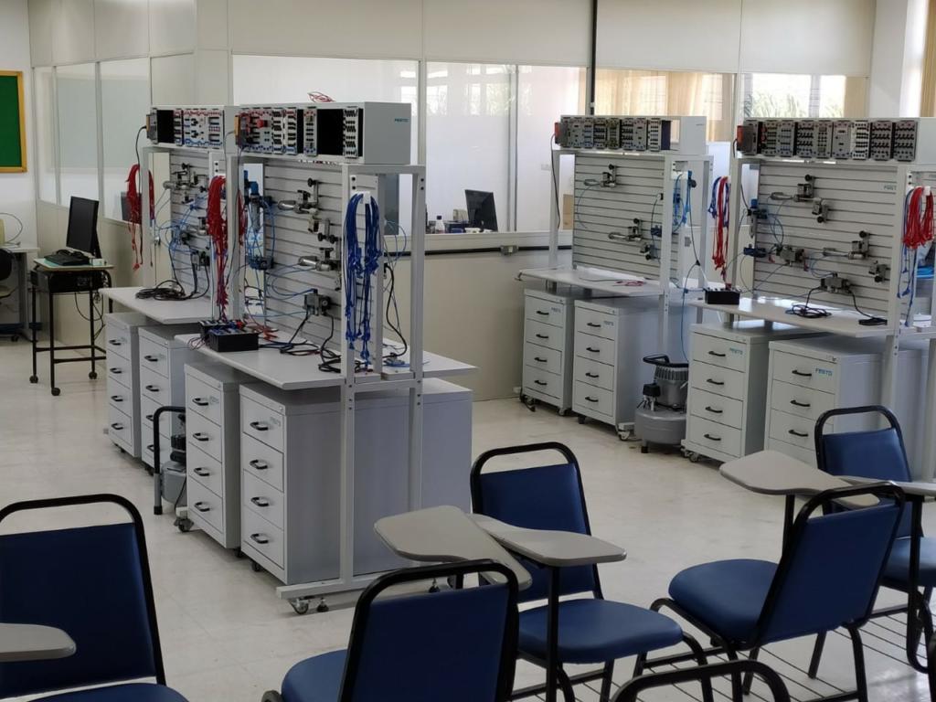 Laboratório com diversas bancadas cinzas com equipamentos
