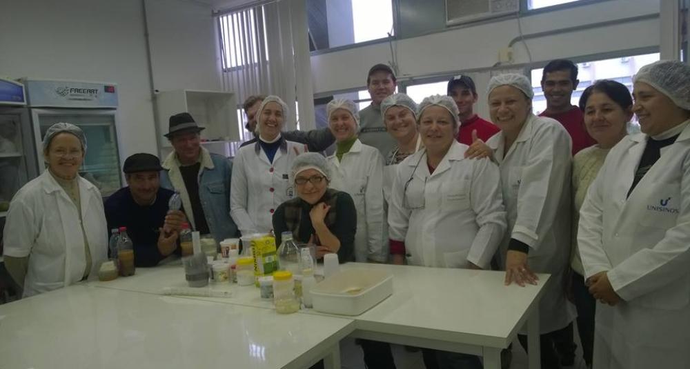 Pessoas de jaleco branco e touca atrás de uma bancada