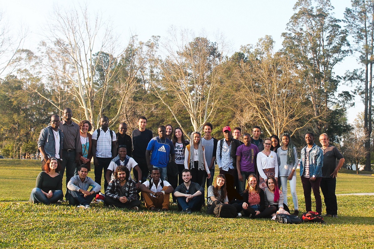 Audiodescrição: na foto, os primeiros estudantes imigrantes e refugiados da Universidade, junto de alunos do Migraidh e servidores da Universidade. fim da audiodescrição