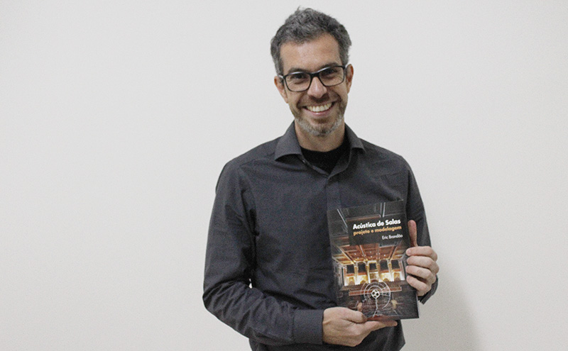 Professor Eric Brandão segurando o livro "Acústica de Salas", do qual ele é autor.