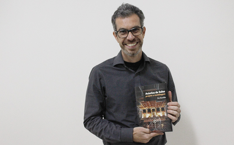 Professor Eric Brand&atilde;o segurando o livro "Ac&uacute;stica de Salas", do qual ele &eacute; autor.