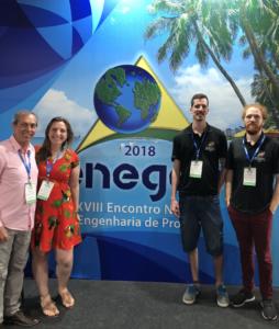 Três homens e uma mulher estão de pé, lado a lado, em frente a um banner do ENEGEP 2018.