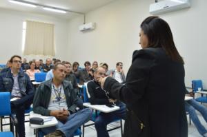Prof. Martha Adaime aparece de costas na fotografia falando para uma sala de aula com docentes sentados.